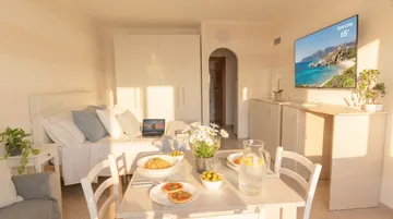 Camera da letto luminosa e accogliente in stile mediterraneo, con biancheria bianca, tazza di caffè e accappatoio